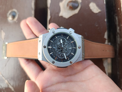 Hand holding a watch with a brown leather strap against a textured surface